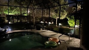 A swimming pool with a glass enclosure, surrounded by a patio area with outdoor furniture and a view of trees. - Private Pool |  Beaches | Golf | Miromar | Baseball No Risk Cancellation (Fort Myers)