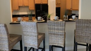 A kitchen with four wicker chairs, a refrigerator, and wooden cabinets. - Private Pool |  Beaches | Golf | Miromar | Baseball No Risk Cancellation (Fort Myers)