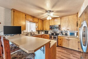 A compact kitchen with wooden cabinets, a built-in microwave, a stove, and a refrigerator.