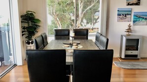 Un coin repas avec une table, des chaises et une vue sur les arbres par la fenêtre.