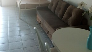 Een kamer met een stapelbed, een slaapbank, een tafel en een stoel.
