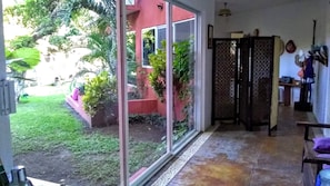 Una habitación con puerta de cristal corredera que da a un jardín, suelo de baldosas y un separador tradicional.