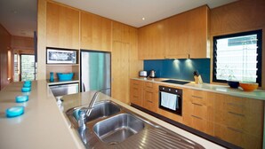 Una cocina moderna con armarios de madera, electrodomésticos de acero inoxidable y un amplio ventanal que proporciona luz natural.