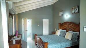 Ein Schlafzimmer mit einem hölzernen Bett, einem Schminktisch, einem Spiegel und einer Tür zu einem anderen Raum.