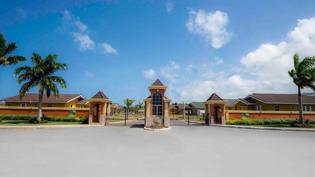 Ein hoteleiser Eingangstor mit einem zentralen Turm, umgeben von Palmen und blauem Himmel.