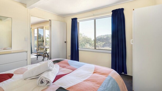 Ein Hotelzimmer mit Bett, einem Vorhangfenster, einer Tür und Blick ins Freie.