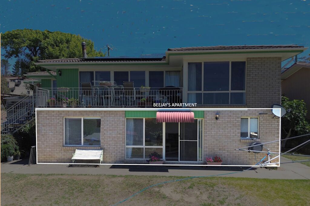Un immeuble de deux étages avec un auvent vert et une enseigne indiquant « BEEJAY'S APARTMENT ».