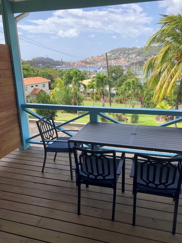 A wooden deck with a table and chairs, overlooking a coastal town with houses and palm trees. - The WINDWARD - Nearby world class marina and great terrace views (Belmont)
