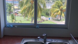A kitchen with a window overlooking a marina, palm trees, and a hilly landscape. - The WINDWARD -  Nearby world class marina and great terrace views (Belmont)
