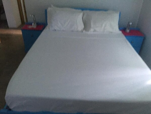 A bed with a white mattress, two nightstands with red and blue bases, and a white pillow.