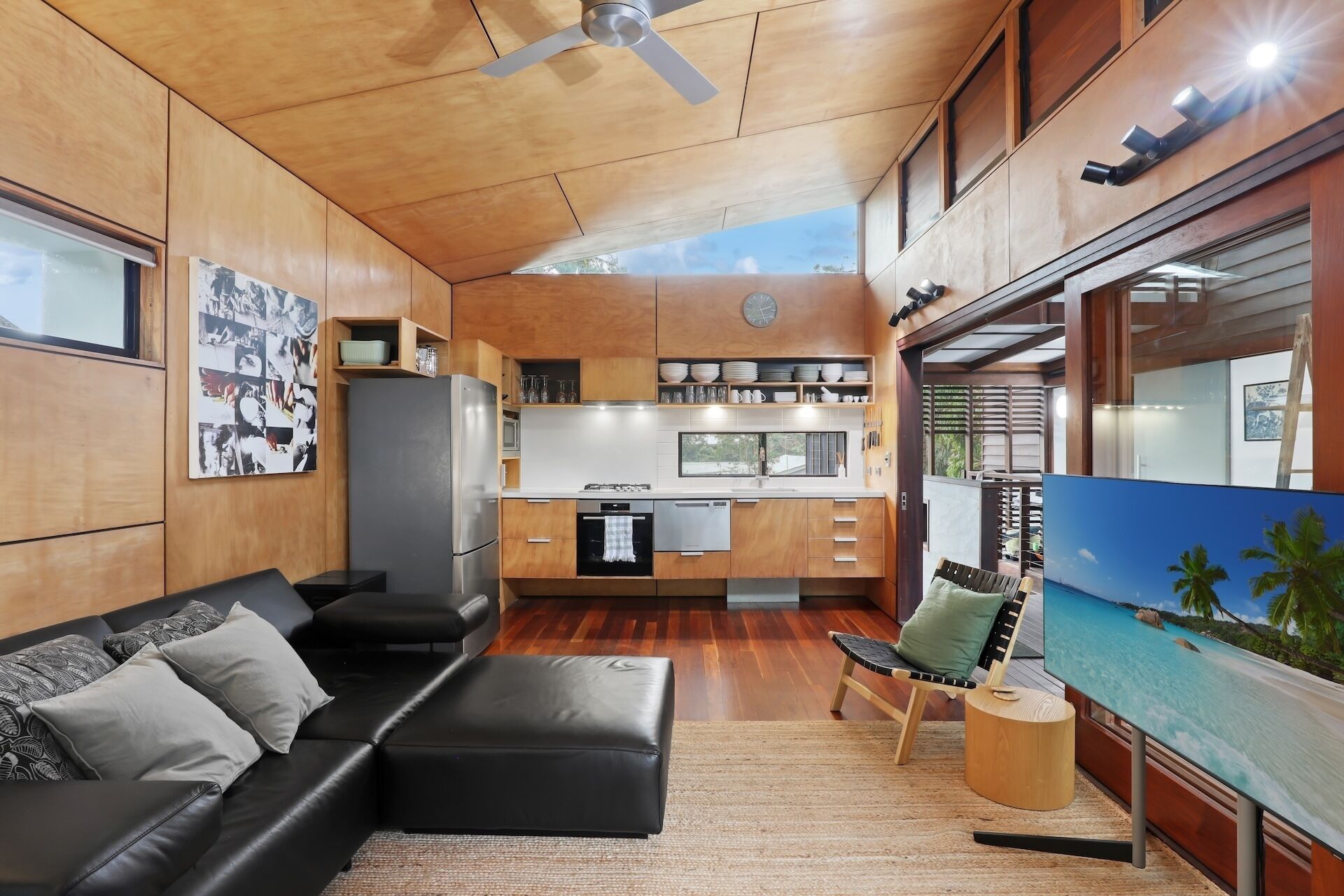 A modern kitchen with wooden cabinets, a refrigerator, and a dining area with a table and chairs.