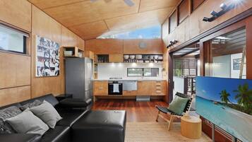 A modern kitchen with wooden cabinets, a refrigerator, and a dining area with a table and chairs.