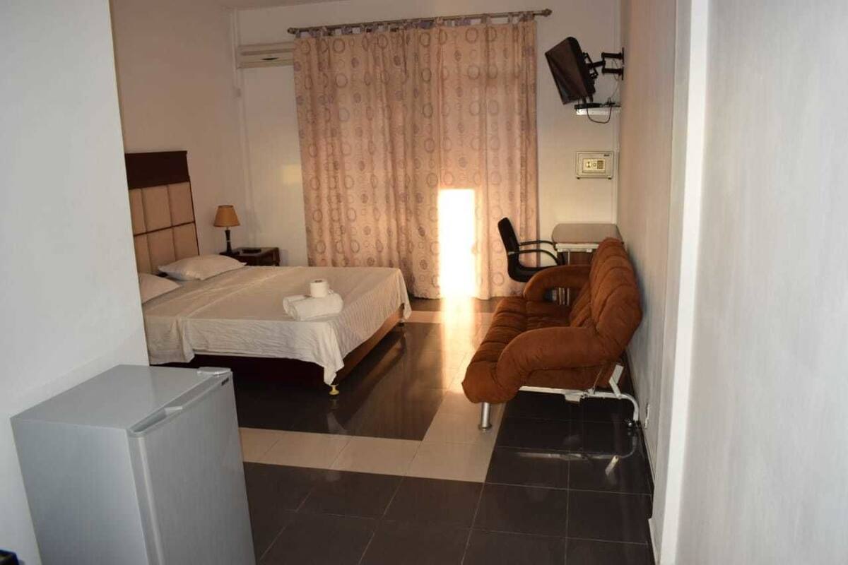 Een hotelkamer met een bed, een bank, een bureau en een koelkast.