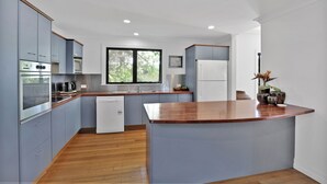 Una cocina moderna con armarios grises, encimera de madera y lavavajillas integrado.