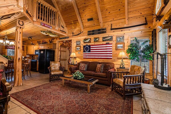 L’intérieur chaleureux de ce chalet est agrémenté de boiseries, d’un coin repas, d’un salon avec un canapé et des fauteuils, ainsi que d’une cuisine équipée d’un réfrigérateur.