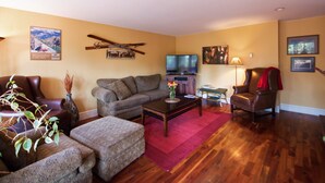 Una sala de estar con sofá, sillón, mesa de centro y televisor.