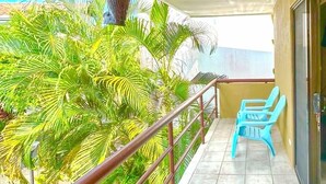 Ein Balkon mit Fliesenboden, einem Metallgeländer und zwei blauen Plastikstühlen.