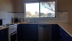 A modern kitchen with a large window, white appliances, and dark blue cabinets. - Bella Views -  Beach front, WiFi and Foxtel!
Availability School Holidays (Ventnor)