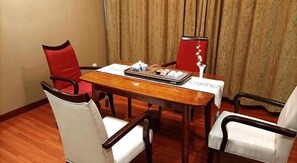 A hotel dining room with a wooden table, four chairs, and a decorative vase.