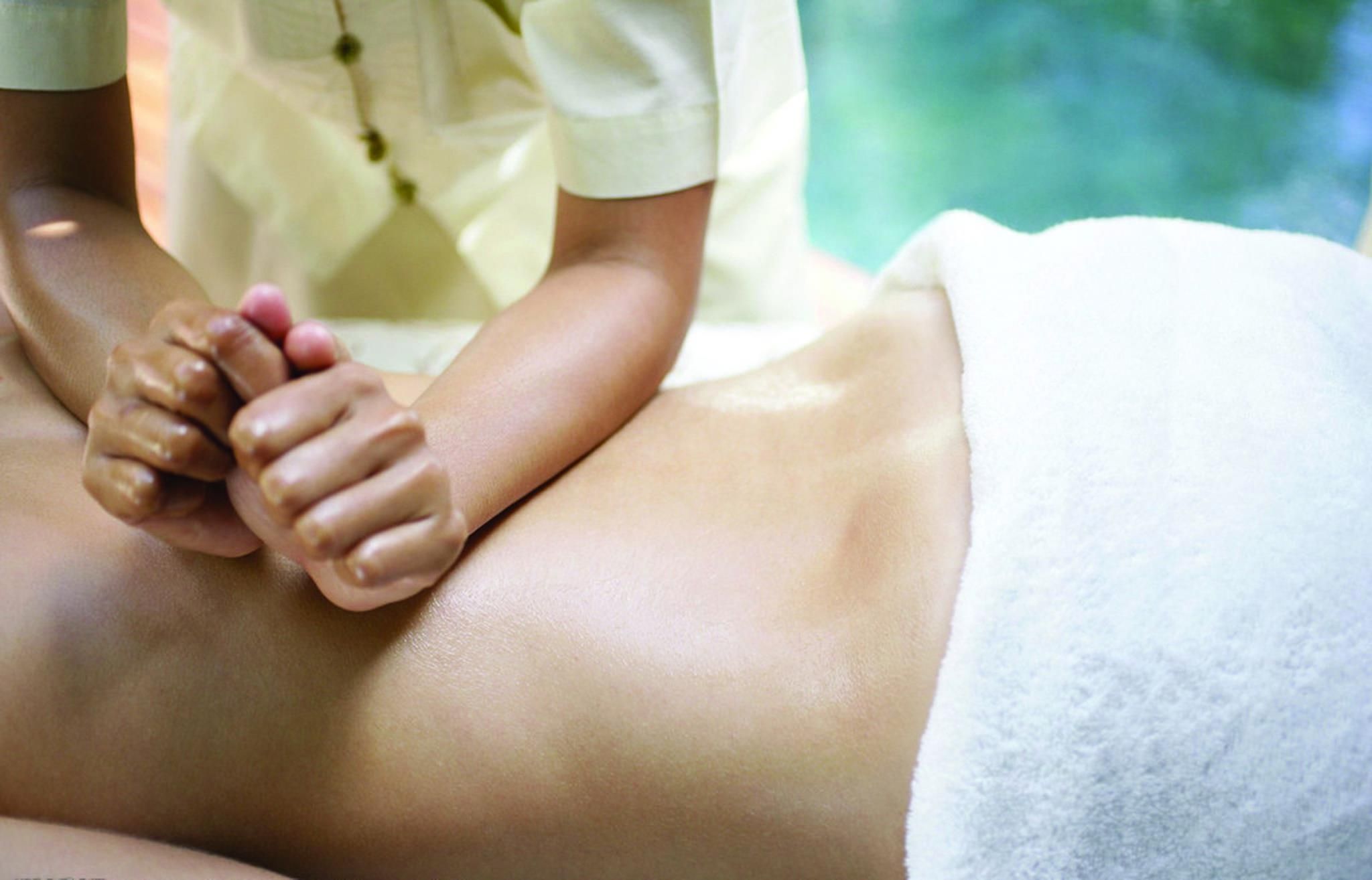 A person receiving a massage with hands resting on their back.