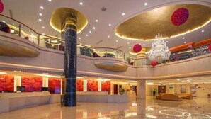 Un vestíbulo amplio con mostrador de recepción, un candelabro y un diseño moderno con techos curvos y una columna de mármol.