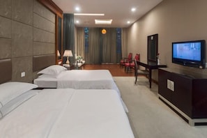 A hotel room with three beds, a desk with a TV, a mirror, and a chair. - Osotto Recreation Hotel (Foshan)