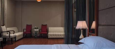 Ein Hotelzimmer mit einem großen Bett, zwei Sesseln, einem kleinen Tisch mit einer Vase und einer Lampe.