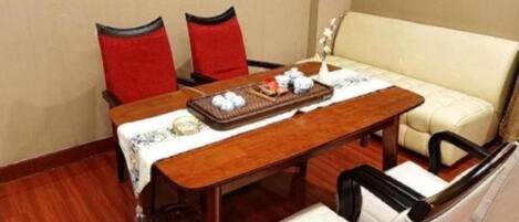 A room with a wooden table, two red chairs, a beige sofa, and a small side table.