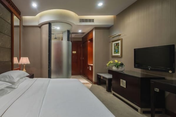 A hotel room with a bed, a desk with a TV, a shower, and a hallway. - Osotto Recreation Hotel (Foshan)
