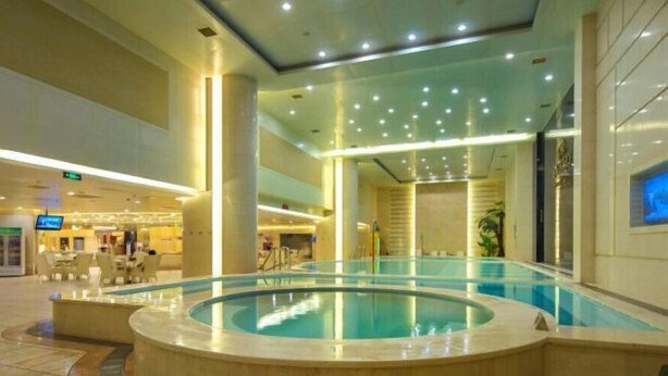 Una piscina interior de diseño circular, rodeada por un suelo de baldosas y un muro de cristal.