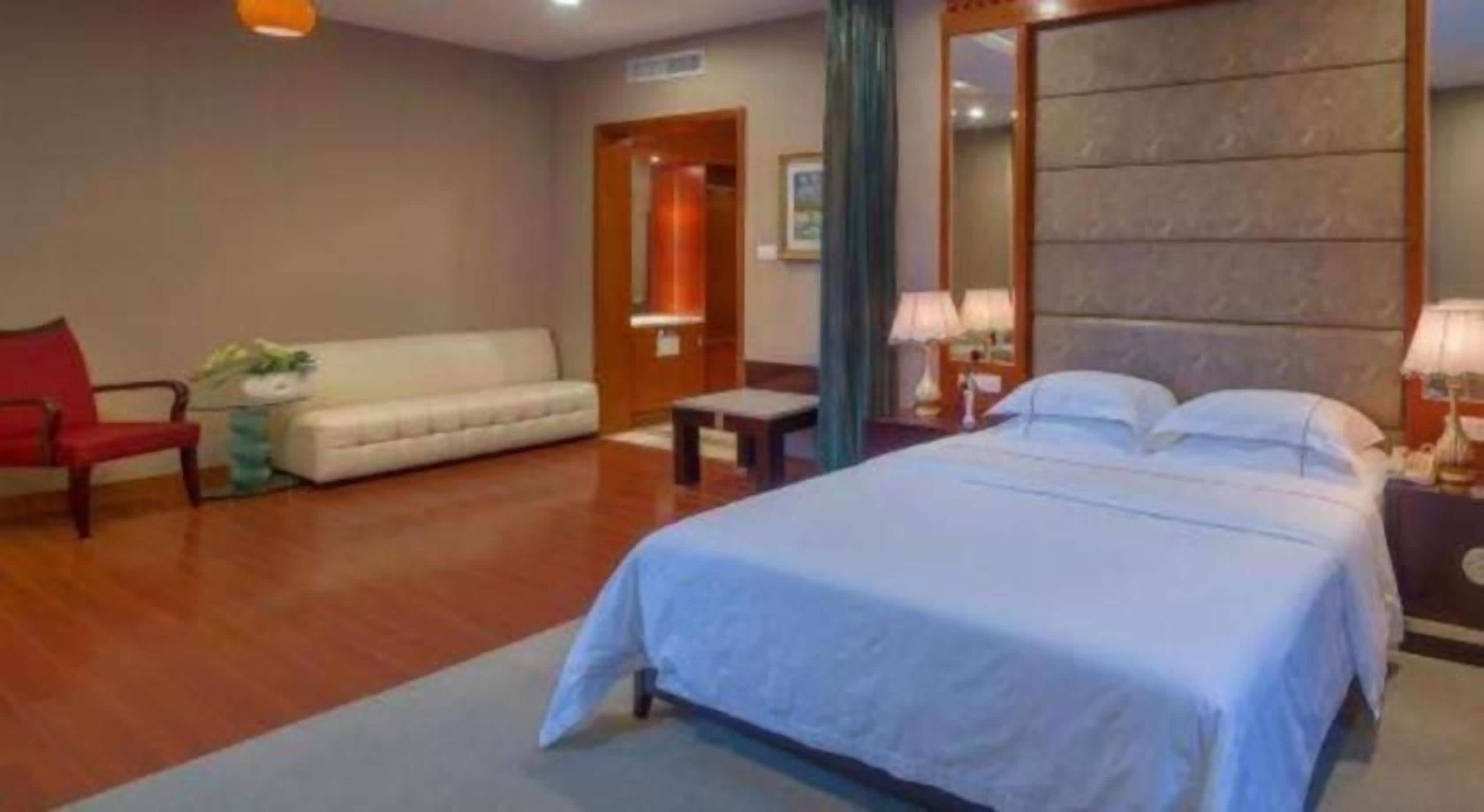 Een hotelkamer met een bed, een bank, een stoel en een bijzettafeltje.