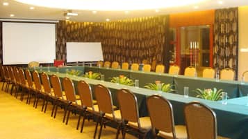 A conference room with a long table, chairs, a projector screen, and a carpeted floor.