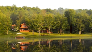 A lodge with a large deck and a pond in front. - Spruce Lake Farm 56-acre mountain-top log home estate on private 7-acre lake (Bovina)
