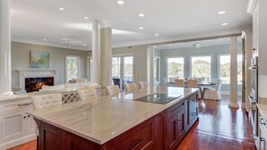 A spacious kitchen with a large island, wooden cabinets, and a fireplace. - 20 Morgan Place Drive by AvantStay | Waterfront Home w/ Private Dock (Isle of Palms)