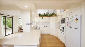 Une cuisine moderne avec des meubles blancs, un îlot central, un four à micro-ondes, un four et un réfrigérateur.