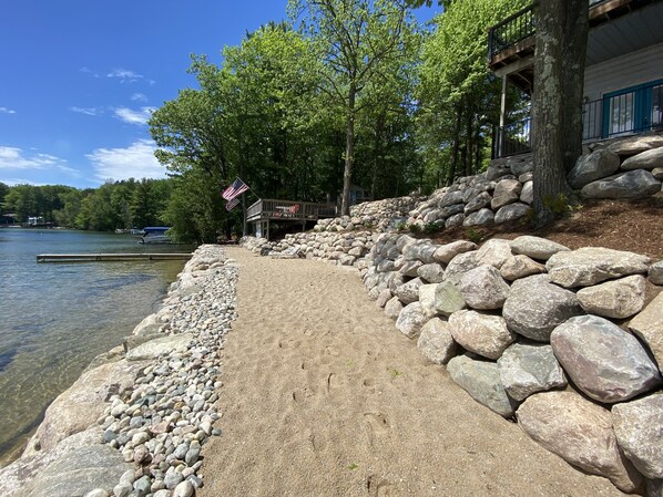 Une promenade au bord du lac, avec une terrasse en bois, de gros rochers et un drapeau américain.
