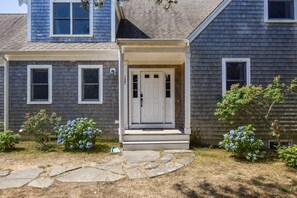 A two-story house with a front porch, a white door, and a mailbox.