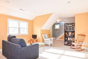 A living room with a sofa, chairs, a television, and a bookshelf.