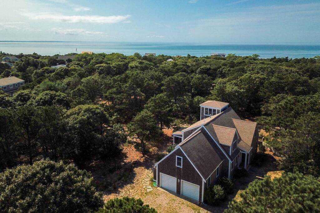 A residential property with a two-story house, a garage, and a view of the sea.