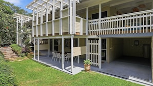 A two-story building with a covered patio area, outdoor seating, and a small garden.