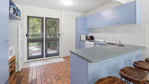 A modern kitchen with a central island, a double sink, and a built-in oven.