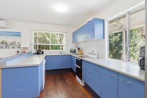 Una cocina moderna con armarios azules, horno empotrado y ventana con vistas a zonas verdes.
