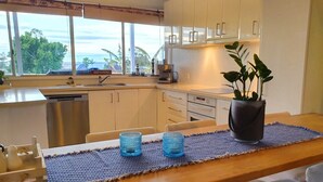 Eine moderne Küche mit weißen Schränken, einem Holzespeisetisch und Blick ins Freie.
