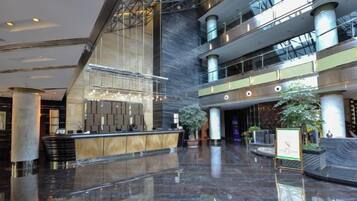 A spacious lobby with a reception desk, large columns, and a high ceiling.