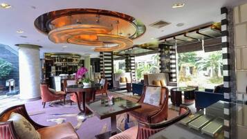 A modern hotel lobby with a round table, comfortable seating, and a large window offering a view of the outdoors.