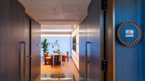 Um hall de hotel moderno com piso de mármore, balcão de recepção e placa na parede com o nome do hotel.