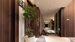 A hallway with wooden paneling, a potted plant, and a carpet with a cow print design.