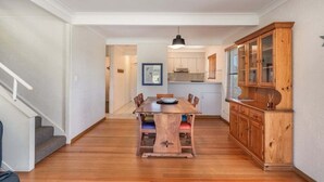 A dining area with a wooden table and chairs, a cabinet with glass doors, and a staircase on the left.