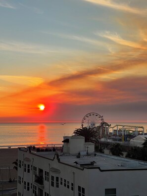Tramonto sull'oceano con una ruota panoramica e edifici in primo piano.