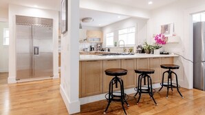 Una cucina moderna con un frigorifero in acciaio inox, pensili in legno e un'isola centrale con sgabelli.